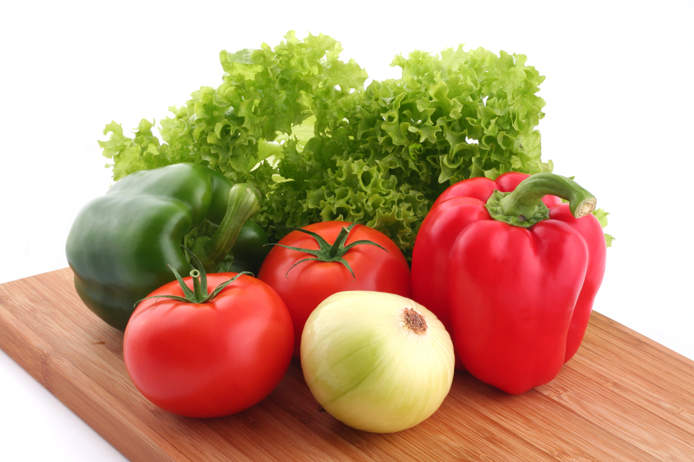 Peppers, salad, tomatoes and onion. Fresh vegetables on kitchen board